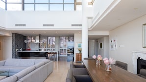 A spacious living area with a kitchen, dining table, and seating. - Penthouse 702 Kylemore B (Stellenbosch)