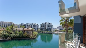 A modern hotel with a pool, surrounded by lush greenery and palm trees, with a clear view of the city skyline in the background. - Penthouse 702 Kylemore B (Stellenbosch)