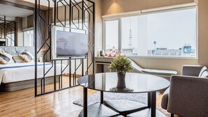 A modern hotel room with a bed, a TV, a round table with a potted plant, and a large window offering a city view. - Hotel 88 Alun Alun (Bandung)