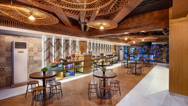 A modern restaurant interior with wooden flooring, round tables, and hanging wicker lamps. - Hotel 88 Alun Alun (Bandung)