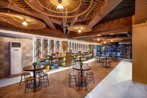 A modern restaurant interior with wooden flooring, round tables, and hanging wicker lamps. - Hotel 88 Alun Alun (Bandung)