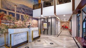 A hotel lobby with a marble reception desk, a mural of a cityscape, and a red scooter in the background. - Hotel 88 Alun Alun (Bandung)