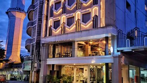A hotel with a modern facade, multiple balconies, and a prominent tower structure in the background. - Hotel 88 Alun Alun (Bandung)