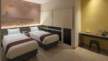 A hotel room with two beds, a desk, and a wall mural.