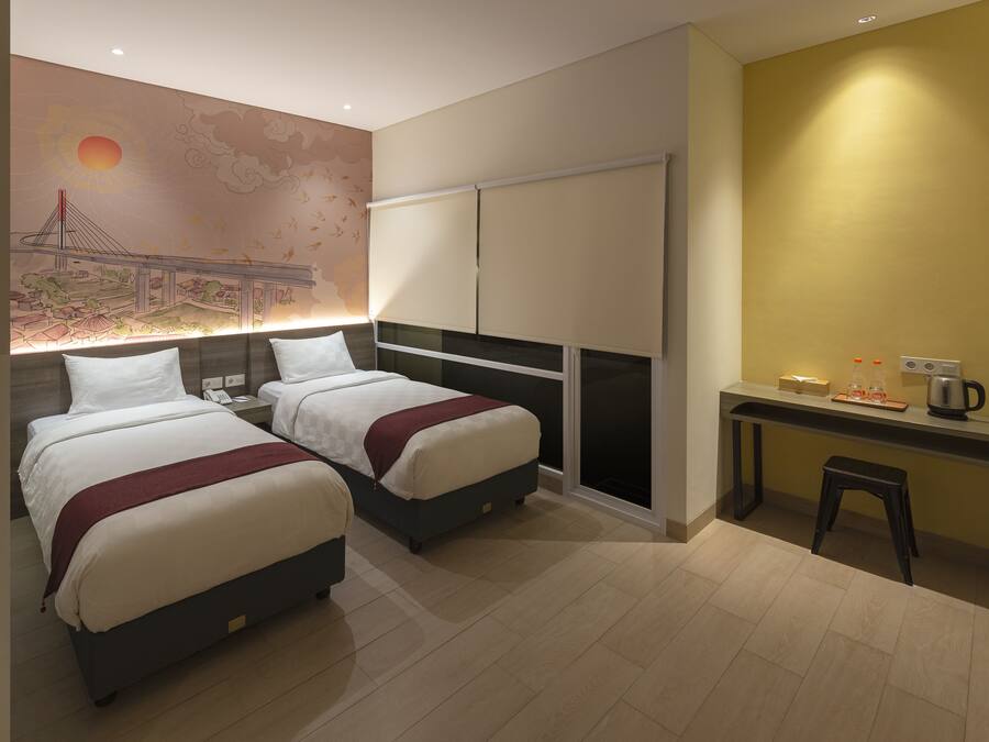 A hotel room with two beds, a desk, and a wall mural.