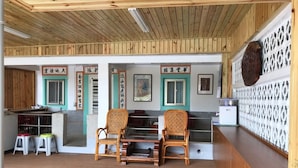 Un espace d’accueil avec un lambris en bois, deux fauteuils en osier, un comptoir et un mur décoratif orné d’œuvres d’art encadrées.