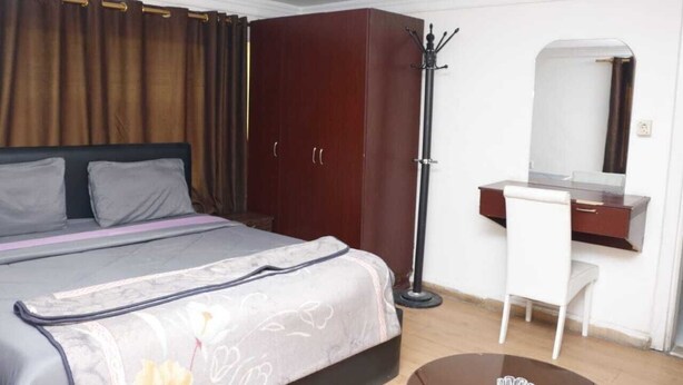 A bedroom with a bed, a desk, a chair, a wardrobe, and a mirror. - Seleen Hotel Suites (Amman)