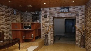 A lobby with a wooden reception desk, a staircase, and a patterned wall. - Seleen Hotel Suites (Amman)