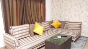 A striped sofa with yellow cushions, a glass-top coffee table, and a patterned wall. - Seleen Hotel Suites (Amman)