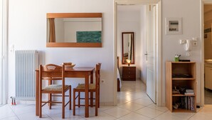 Ein Zimmer mit Holztisch, Stühlen, einem Spiegel, einer Heizung und einem Bücherregal.