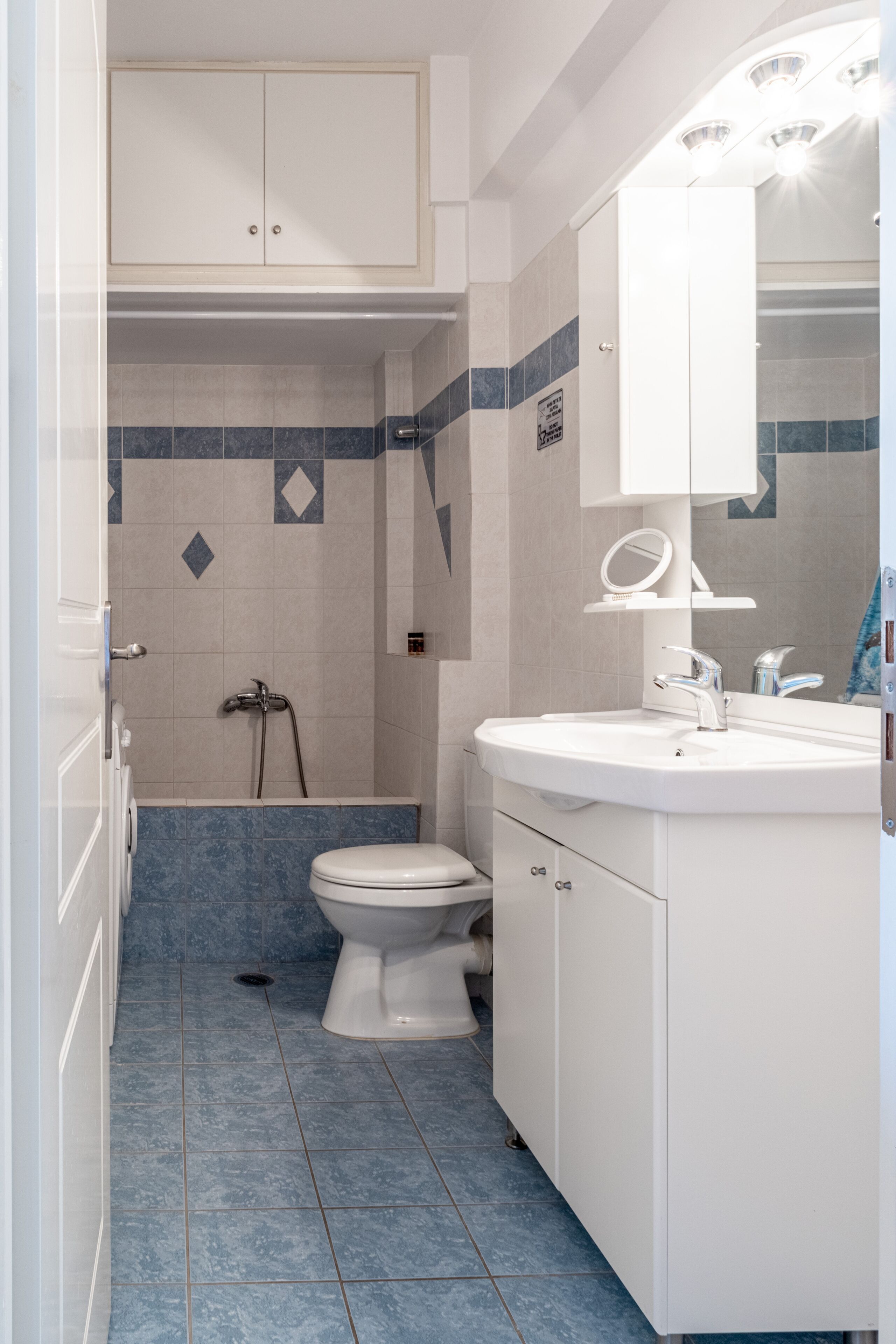 A bathroom with a white toilet, a sink with a mirror, and a shower area.