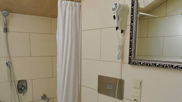 Un baño con bañera, inodoro, lavamanos y un secador de pelo en la pared.
