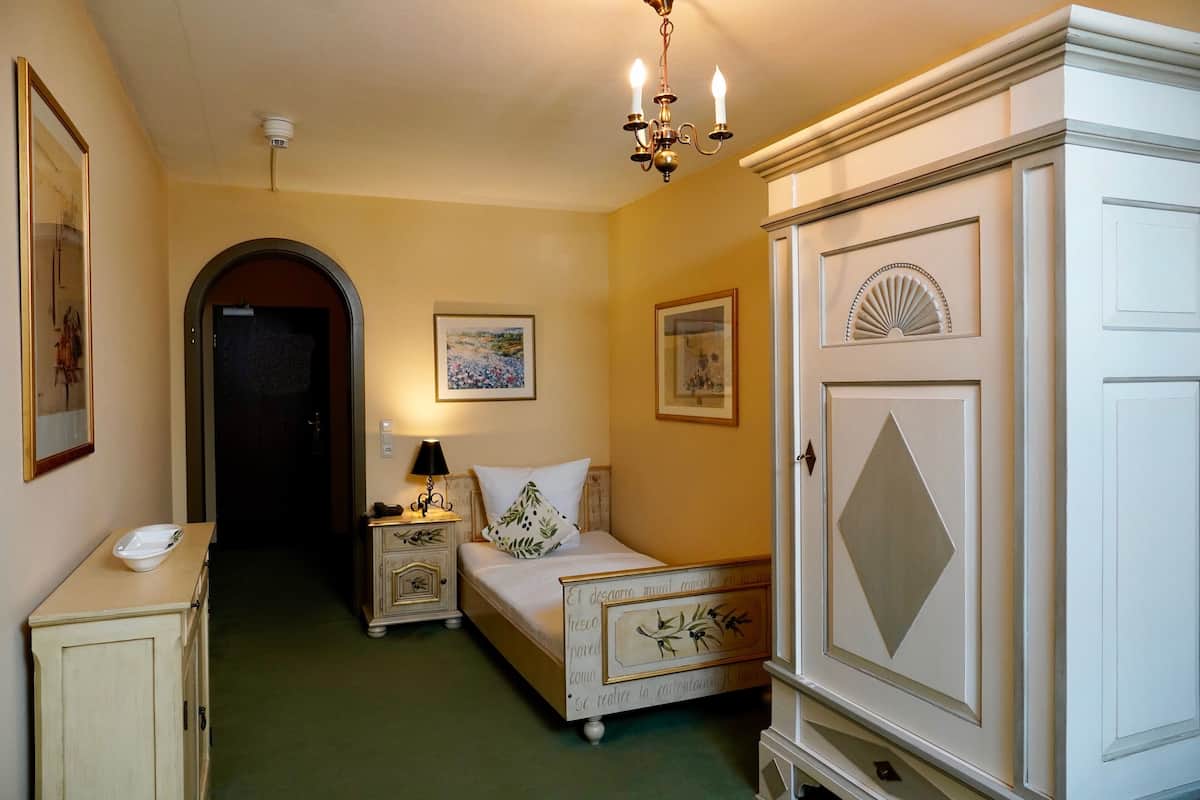 A bedroom with a bed, bedside table, lamp, and a wardrobe.