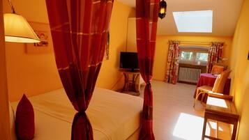 A bedroom with a bed, curtains, a television, a chair, and a table.