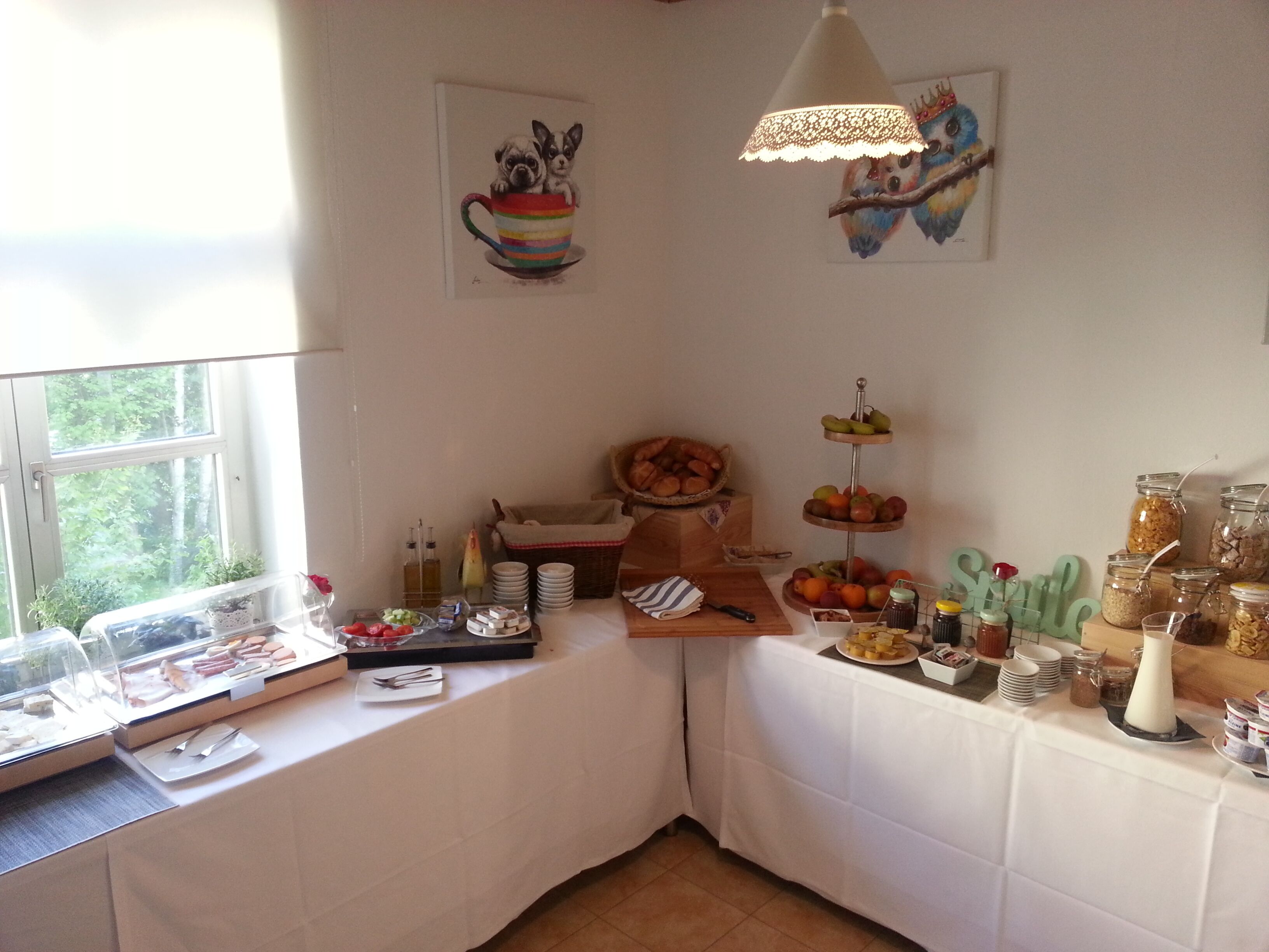 Een buffetopstelling met diverse gerechten en een decoratief schilderij van een vogel op een tak.
