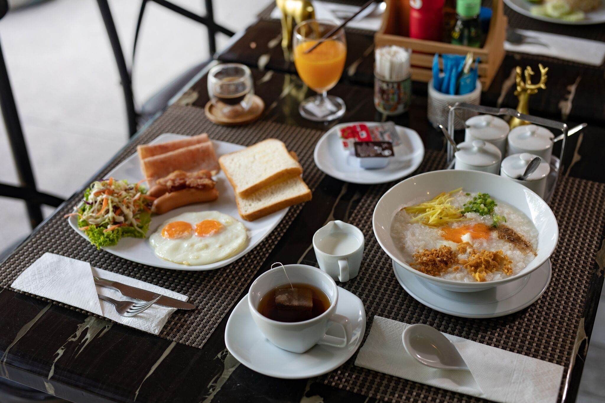 Une table de petit-déjeuner avec des assiettes de toasts, des œufs et un bol de porridge, ainsi qu’une tasse de thé.