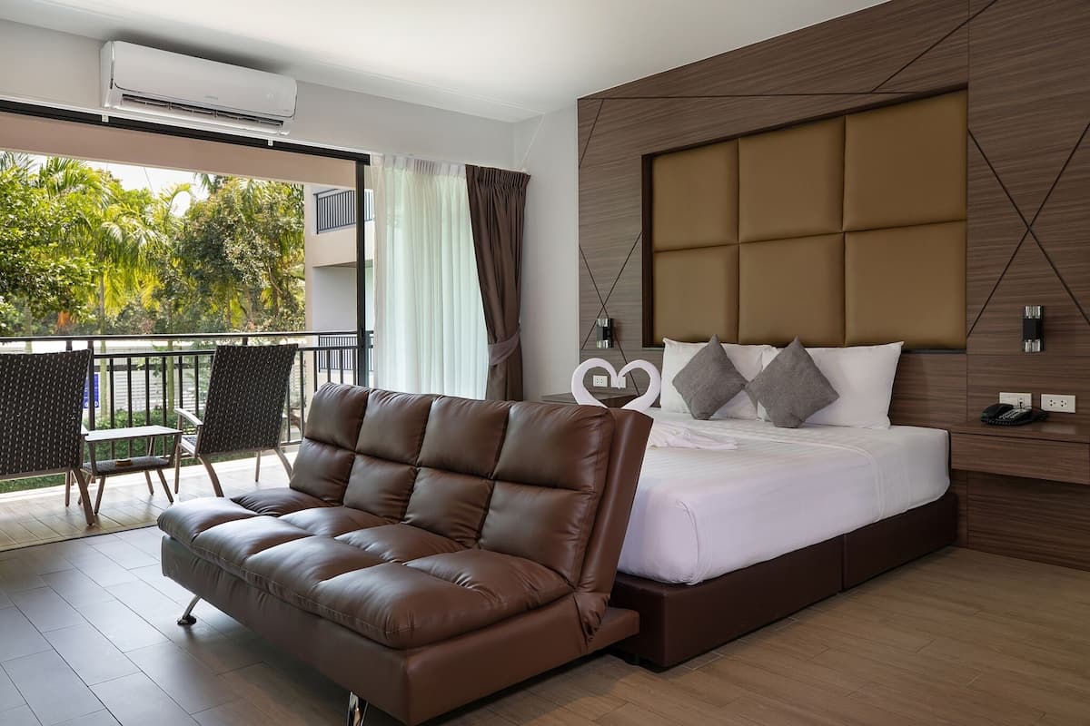 Una habitación de hotel moderna con una cama grande, un sofá de cuero y un balcón con vistas a zonas verdes.