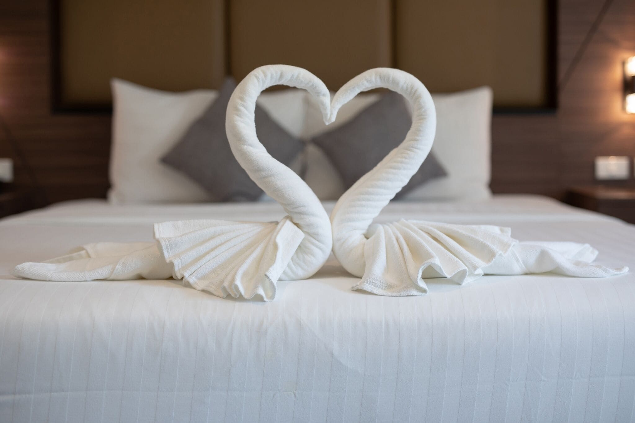 A bed with a heart-shaped towel arrangement.