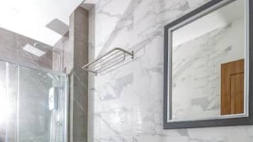 Un baño moderno con cabina de ducha de vidrio, inodoro blanco y salpicadero de mármol.