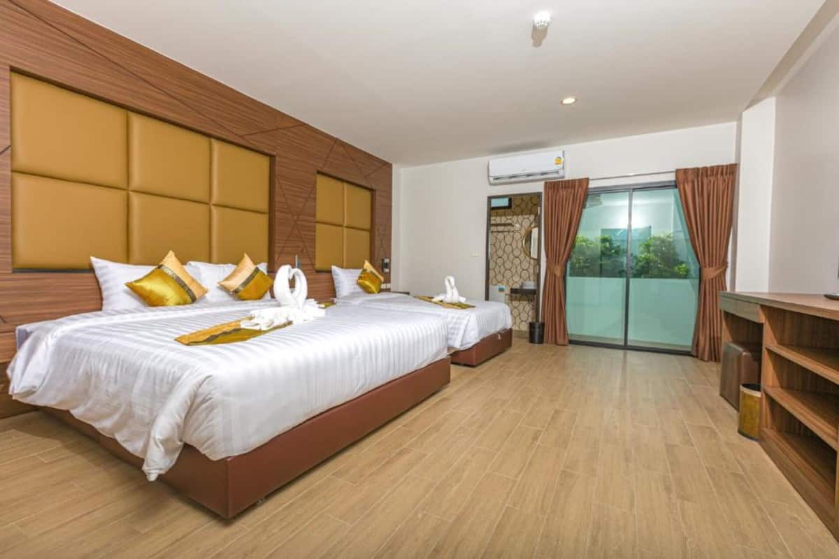 Habitación de hotel con una cama grande, un escritorio y vistas a la vegetación por la ventana.