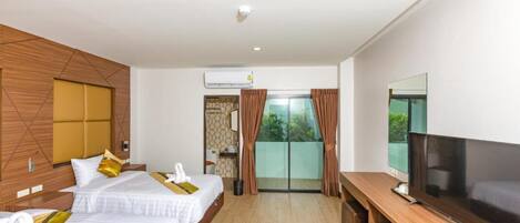 A hotel room with two beds, a TV, a balcony with curtains, and an air conditioning unit.