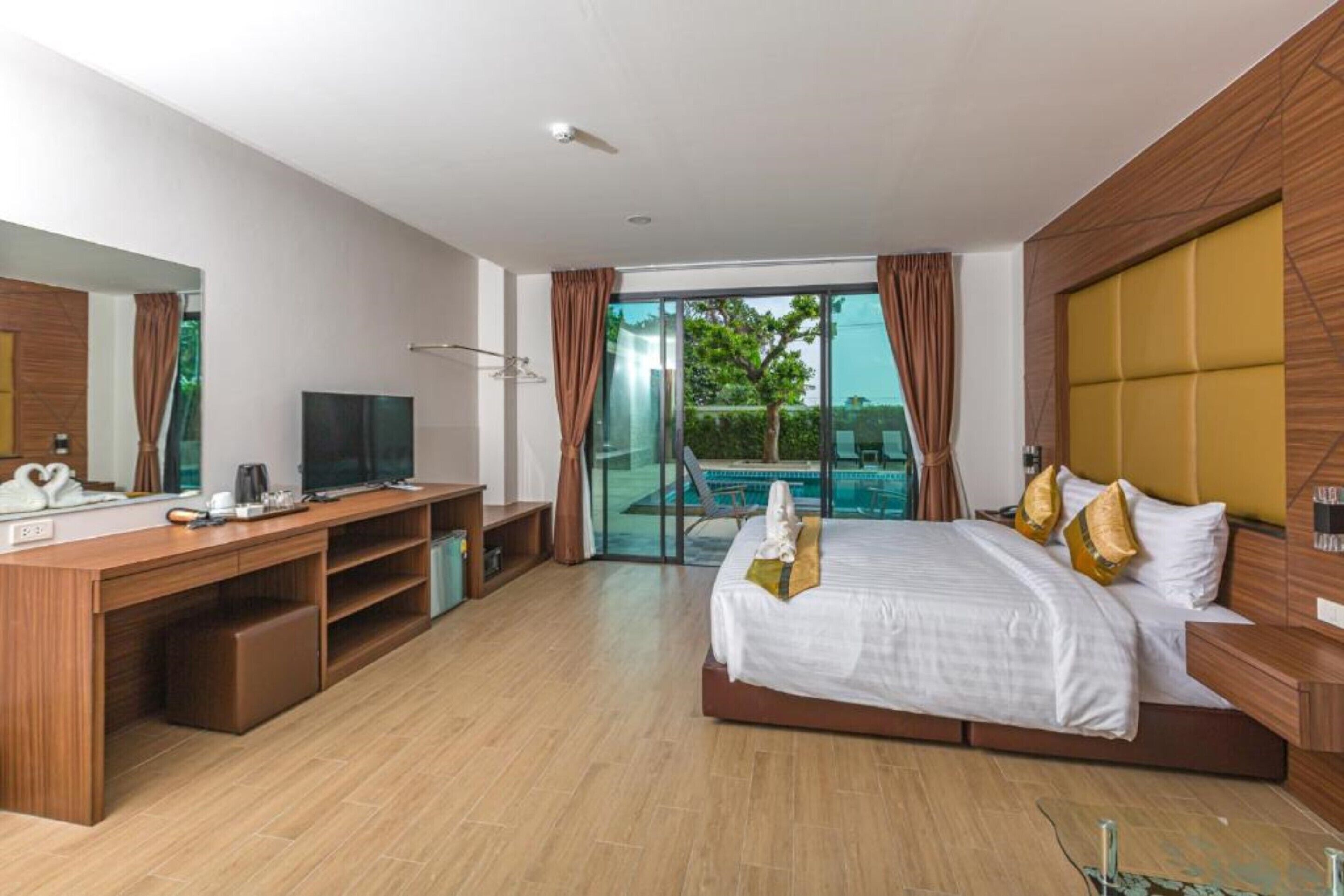 Une chambre d’hôtel moderne dotée d’un grand lit, d’un bureau avec une télévision, d’une porte vitrée donnant sur une piscine et offrant une vue sur la verdure environnante.