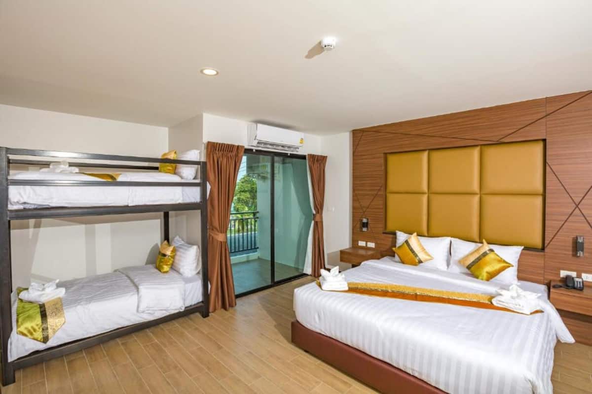 Habitación de hotel con literas, una cama individual y una puerta corrediza de vidrio que da a un balcón.