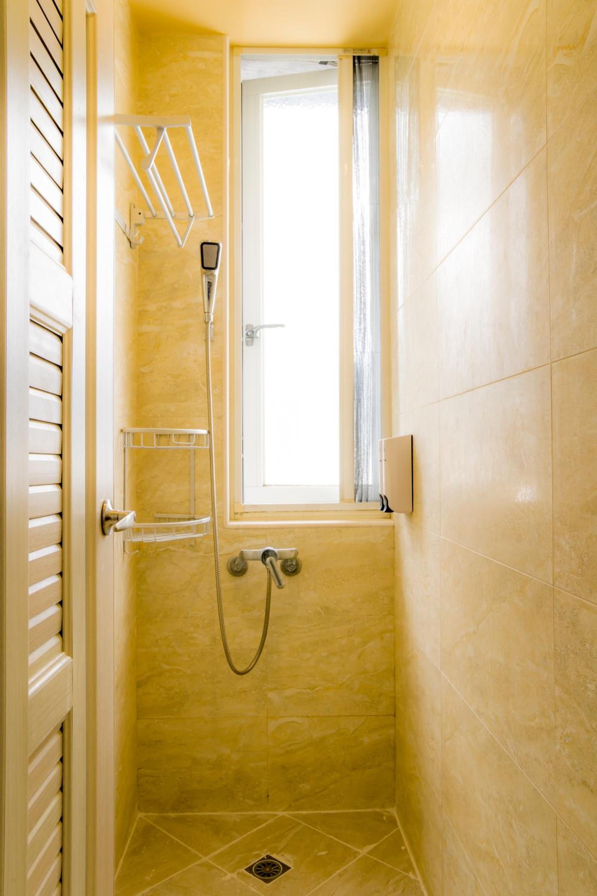 A small, enclosed shower area with a window, a towel rack, and a shower control panel.