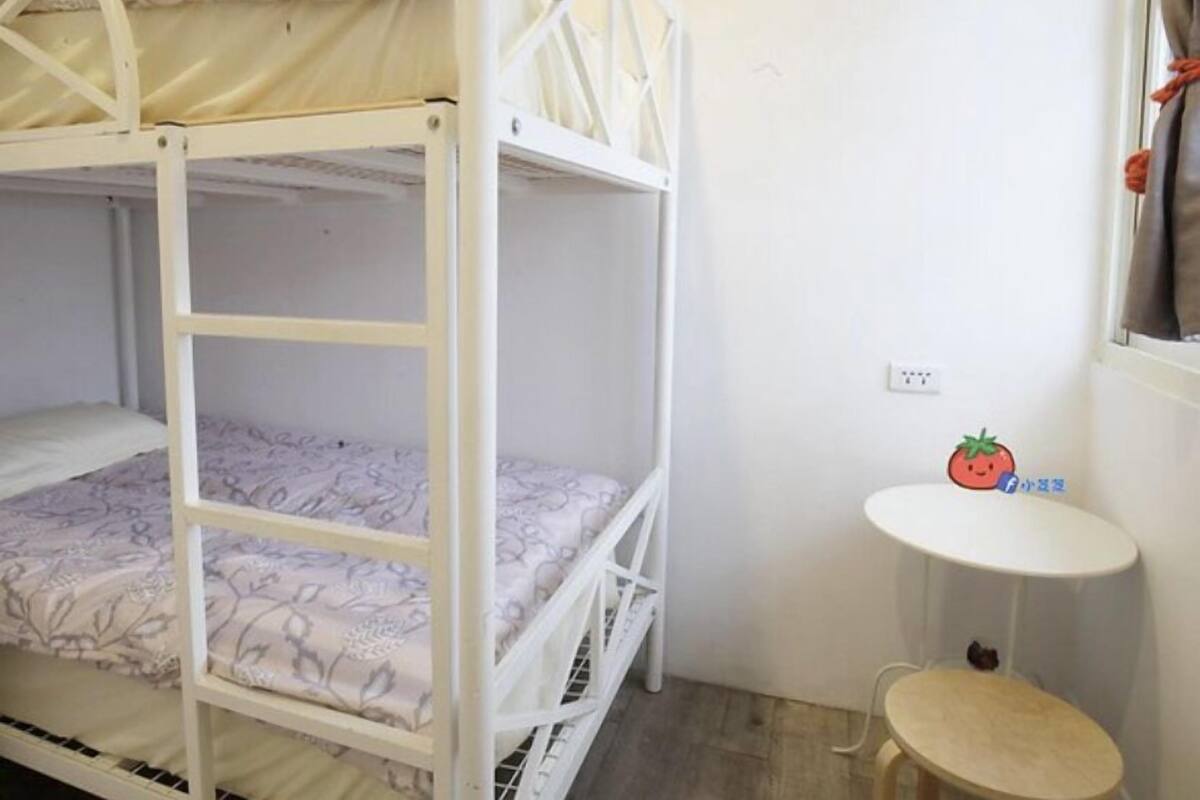 Une chambre avec un lit superposé, une petite table et une fenêtre.