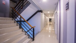 Un couloir d’hôtel moderne avec un escalier, un panneau « Interdiction de fumer » et un panneau « 2e étage ».