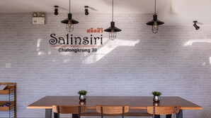 Un espace repas moderne avec un mur en briques, des suspensions décoratives et une table en bois entourée de chaises.