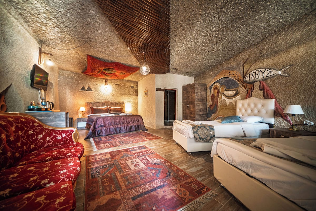 A cozy, rustic bedroom with a large bed, a sofa, and a patterned rug.
