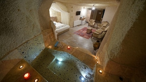 A cozy, stone-walled bedroom with a large bed, a sitting area with a chair, and a small bathroom. - Adelya Cave Hotel (Nevsehir)