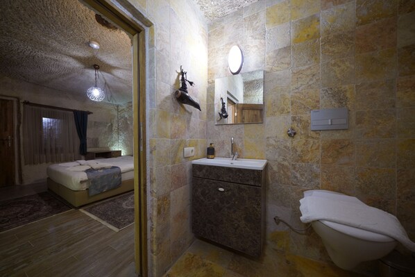 Une salle de bain avec un lavabo en marbre, des toilettes et un miroir.