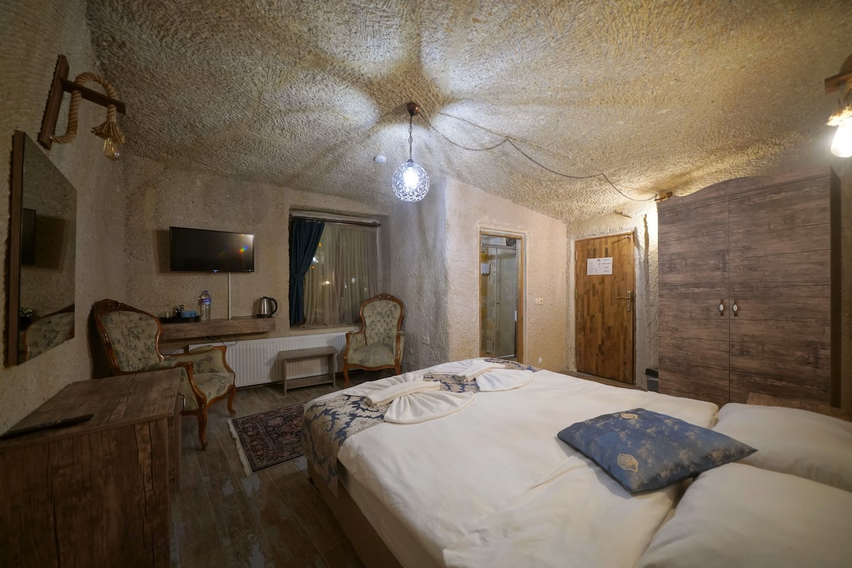 A cozy room with a bed, a desk, a chair, a television, and a wardrobe.