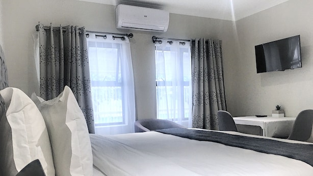 A hotel room with a bed, a desk, a chair, and a TV on the wall. - Selton Guest House (Cape Town)