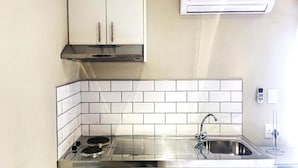 A compact kitchen with white cabinets, a stainless steel sink, and a built-in stove. - Selton Guest House (Cape Town)