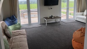 A living room with a sofa, bean bag, and a TV on the wall. - Atiamuri Bach Family (Atiamuri)