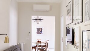 Ein modernes Wohnzimmer mit einer Couch, einem Esstisch mit Stühlen und einem Flur mit gerahmten Bildern an den Wänden.