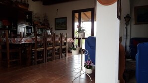 A dining area with wooden chairs and a tiled floor, a blue chair, and potted plants. - Affittacamere Luti (Oristano)