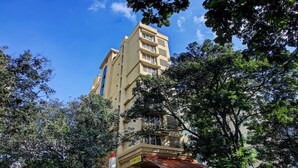 A multi-story building with a flat facade, surrounded by trees. - Treebo Trend Blue Bells Residency (Mumbai)