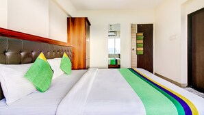 A hotel room with a large bed, a wooden headboard, and a view of the city through the window. - Treebo Trend Blue Bells Residency (Mumbai)