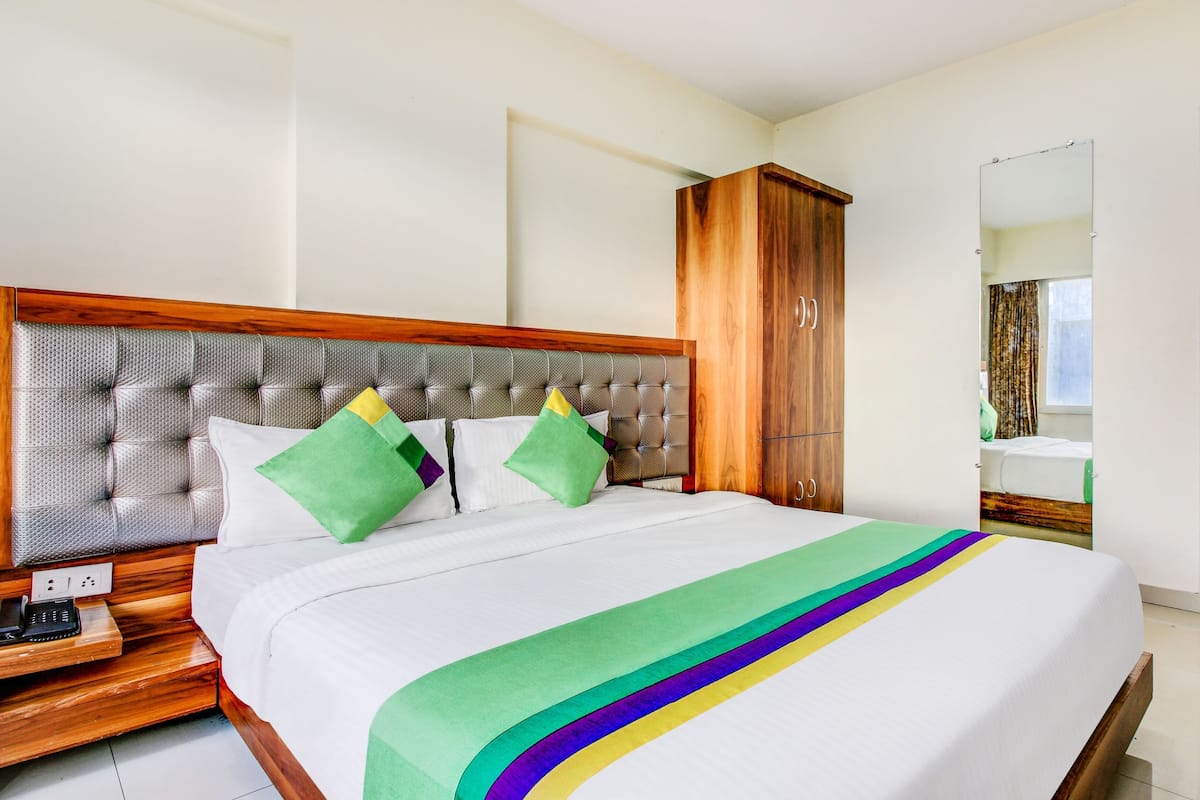 Una cama bien hecha con una colcha a rayas, un cabecero de madera y un armario de madera.