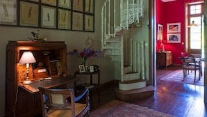 Habitació amb escala espiraltra, quadres als murs, escriptori amb làmpada i cadira.