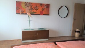 A room with a bed, a bedside table with a vase of flowers, a mirror, and a painting on the wall. - Cozy vacation apartment "Schwalbennest" under the roof with garden access (Bundenthal)