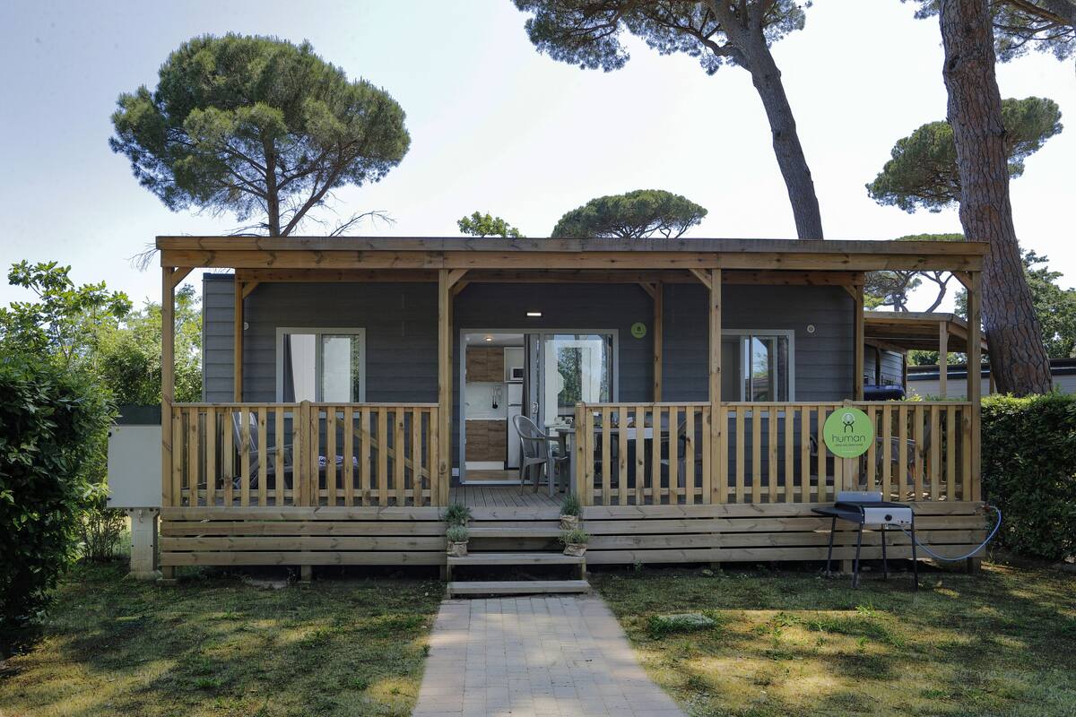 Eine Holzhütte mit Veranda, einem kleinen Tisch und einem Stuhl.