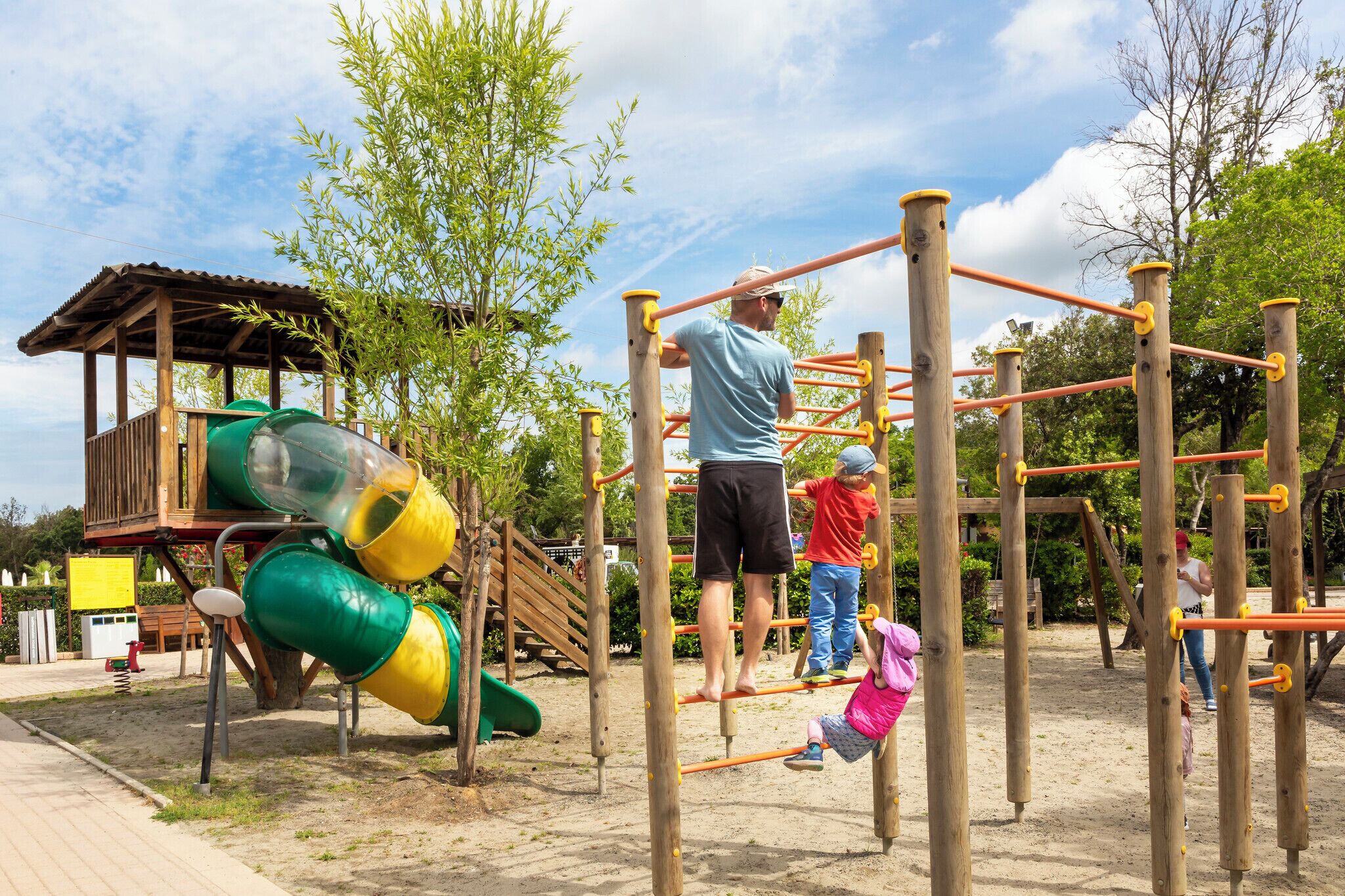 A playground with a wooden climbing structure, a slide, and a covered play area.