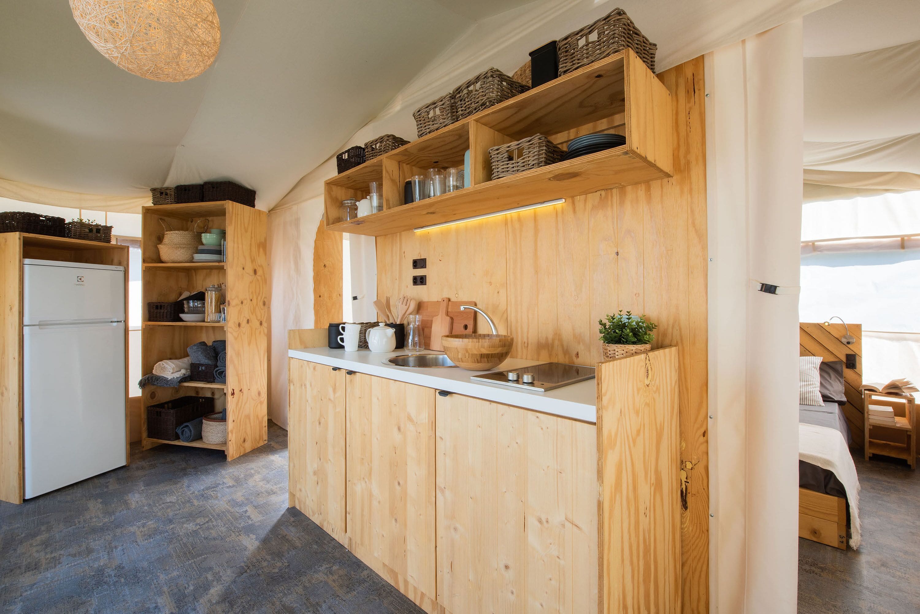 A compact kitchen with wooden cabinetry, a built-in sink, and a refrigerator.