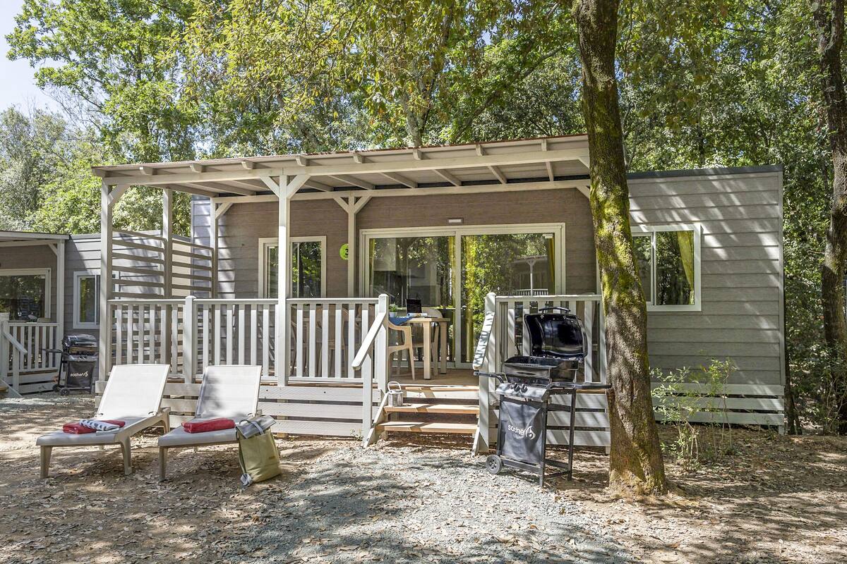 Eine Hütte mit überdachter Veranda, Sitzgelegenheiten im Freien und einem Grill.