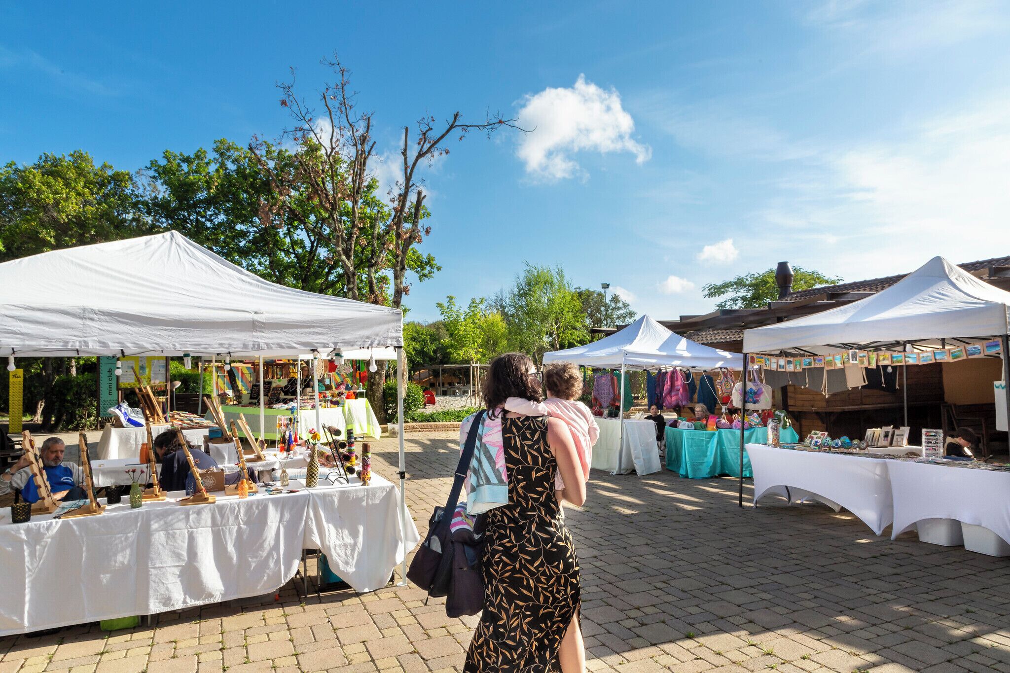 Un mercado al aire libre con carpas blancas y mesas que exhiben diversos artículos.